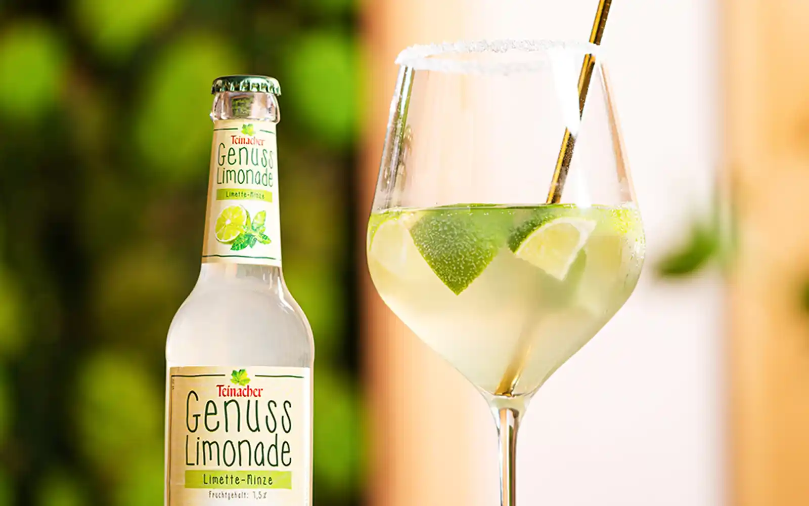 Nahaufnahme der Teinacher Genusslimonade Limette-Minze mit Glas Summer Spritz, Limettenscheiben und Strohhalm.