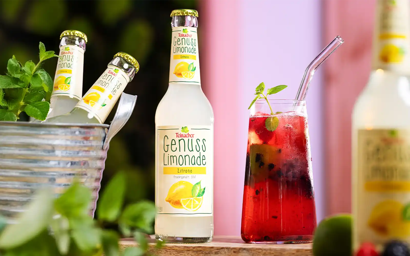 Teinacher Genusslimonade Zitrone in Flasche und Glas mit Virgin Berry Lemon Mocktail, frischen Beeren und Minze.